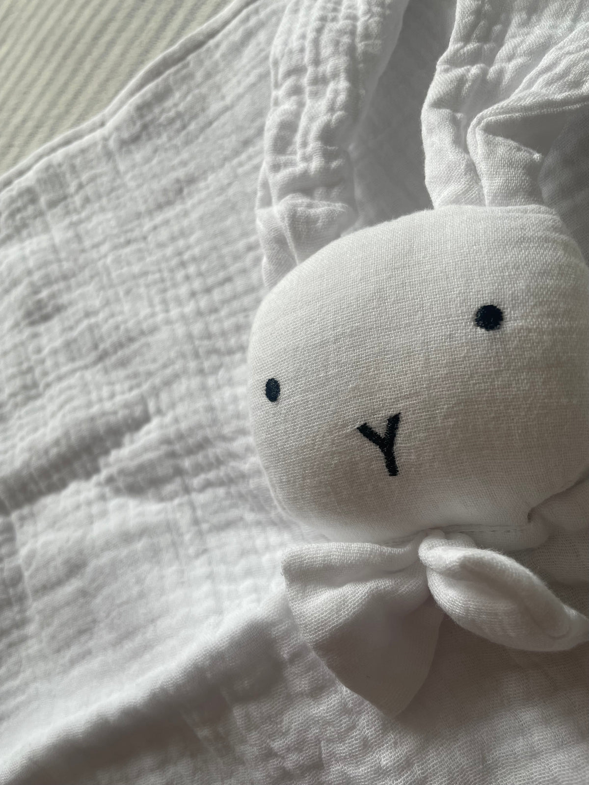 Gros plan du visage brodé du doudou lapin en mousseline de coton V.Lune